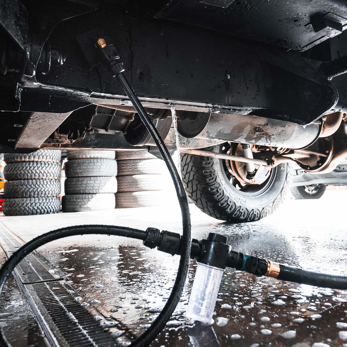 Actual cleaner mounted under a truck, with connecting hose and reservoir